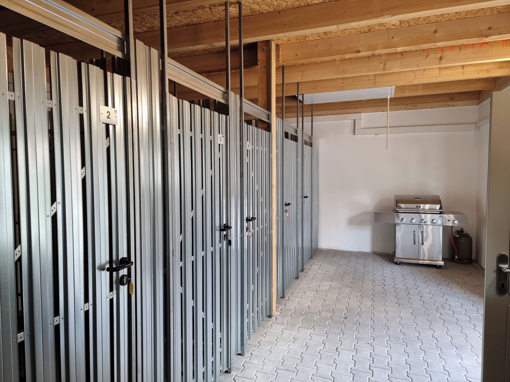 Ein Zimmer mit Metallschränken, einer Küchenzeile mit Herd und einem Fliesenboden.