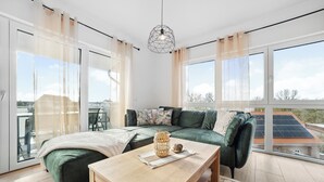 Una sala de estar moderna con un sofá verde, una mesa de centro de madera y vistas a paneles solares.