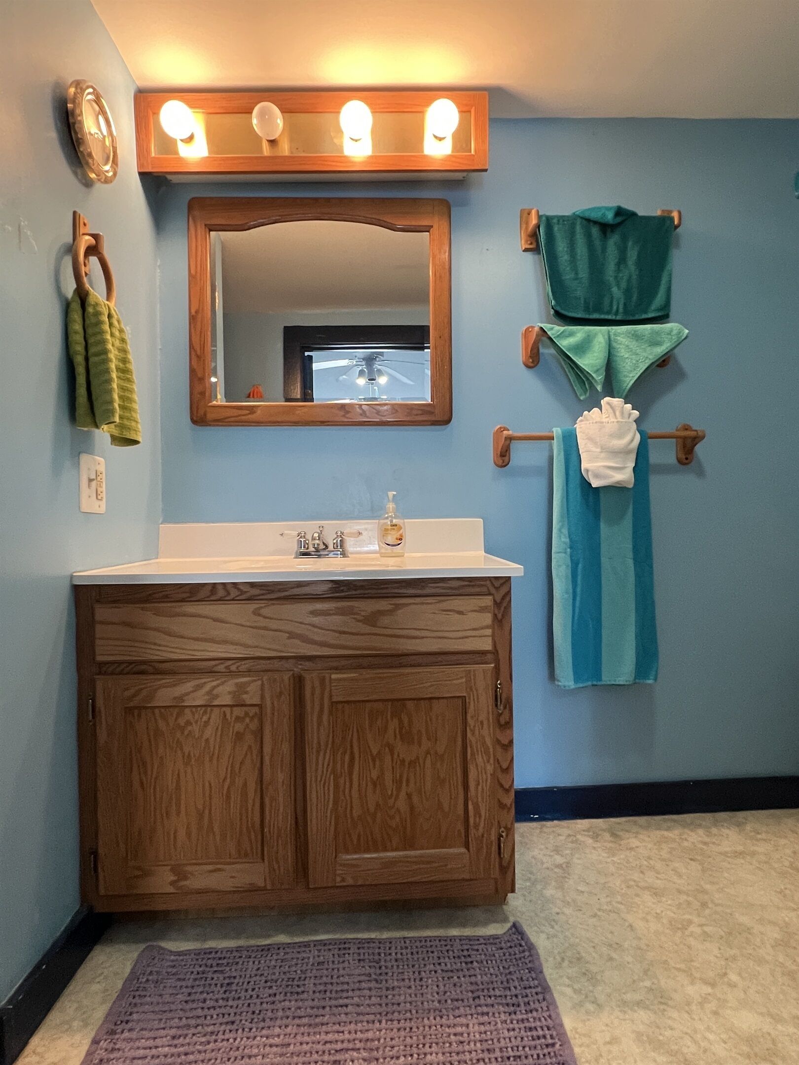 Une salle de bain avec un meuble-lavabo en bois, un miroir avec éclairage intégré et des serviettes suspendues sur un porte-serviettes.