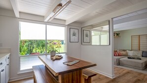A modern kitchen with a wooden island, large windows, and a view of greenery.