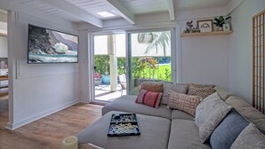 A cozy living room with a large sofa, a chessboard, and a painting of a coastal scene.