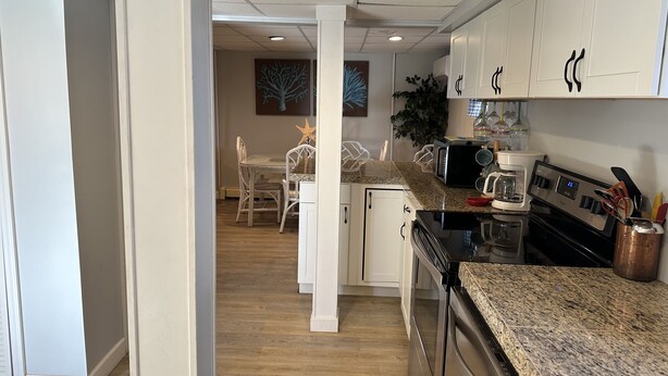 A modern kitchen with white cabinets, granite countertops, and stainless steel appliances.