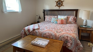 A neatly arranged bedroom with a bed, bedside table, lamp, and a wall clock.