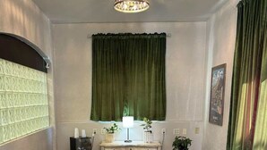 A room with a chandelier, green curtains, a patterned rug, and brown leather chairs around a central coffee table. - Deluxe Room at The Block (Bisbee)