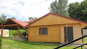 Een houten chalet met een rood dak, een deur en een raam.
