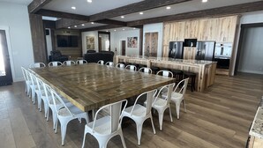 Une cuisine spacieuse avec un grand îlot central en bois, des chaises blanches et des appareils électroménagers modernes.
