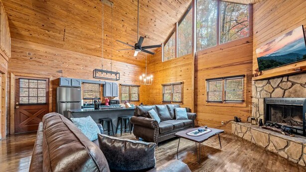 A spacious cabin interior with a living area, kitchen, and fireplace.