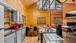 A modern log cabin with a kitchen, dining area, and living room.