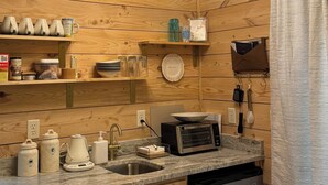 Eine kleine Küche mit Holzvertäfelung, eingebautem Spülbecken, Toasterofen und verschiedenen Küchenutensilien.