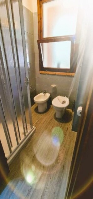 Un baño con inodoro, bidé y una ventana sobre el lavabo.