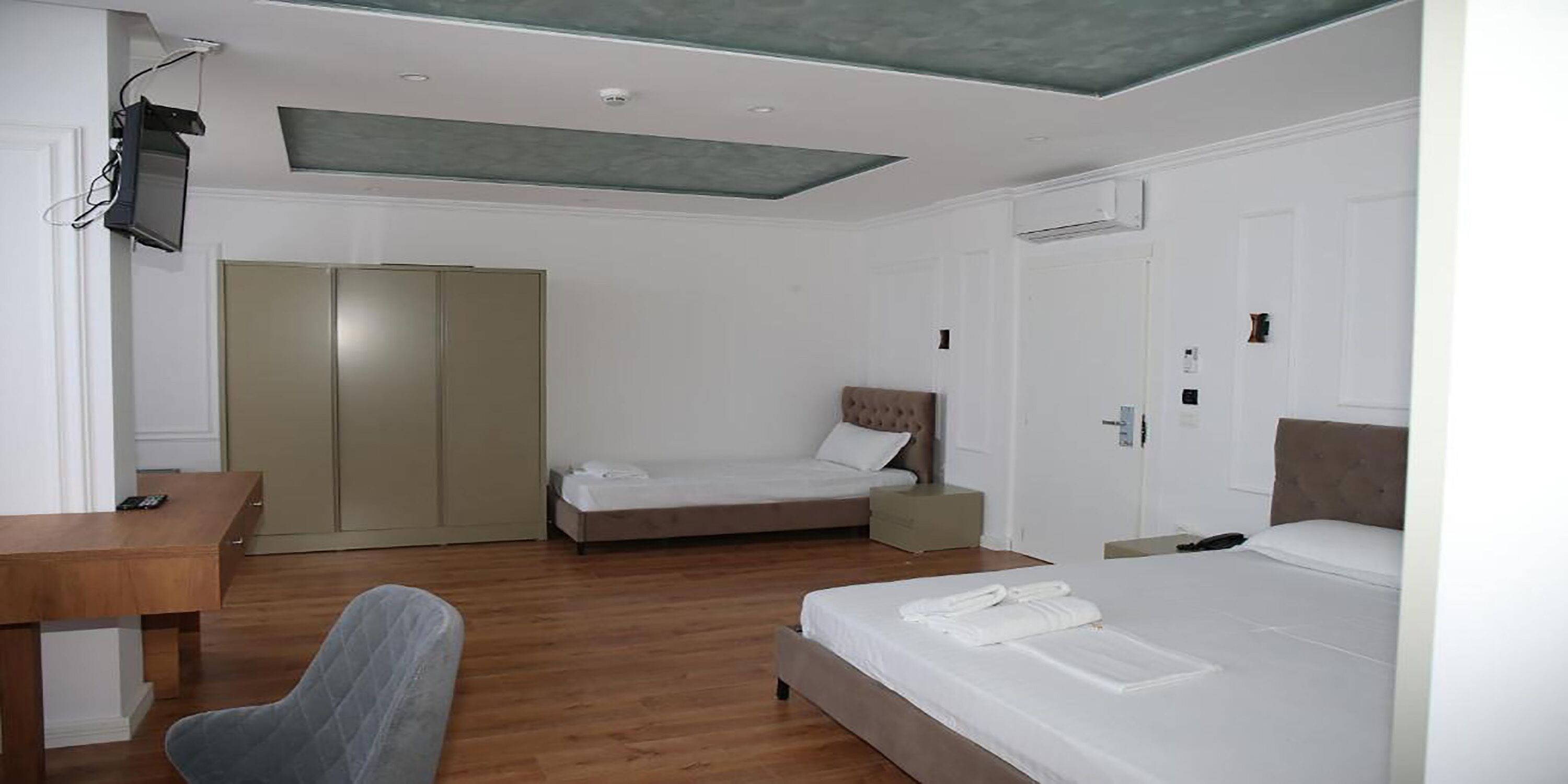 A hotel room with a bed, a desk, a chair, and a wardrobe.