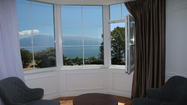 A corner room with a large bay window offering a scenic view of the sea and mountains. - Pashkaj Hotel (Udënisht)