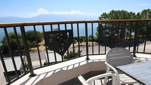 A balcony with a view of the sea and mountains, a table, and two chairs. - Pashkaj Hotel (Udënisht)