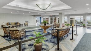 A spacious lobby with a high ceiling, a central seating area with a round table, and a coffee shop in the background. - Bay Watch 632 - Multiple Pools, Hot Tubs, & Lazy River (North Myrtle Beach)