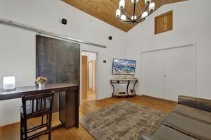 Ein modernes Wohnzimmer mit einem dunklen Holztisch, einem Ledersofa, einem gemusterten Teppich und einem großen Gemälde an der Wand.