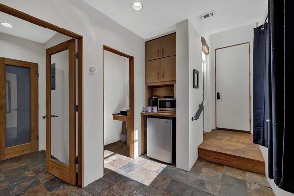A compact kitchen with a microwave, refrigerator, and wooden cabinets.