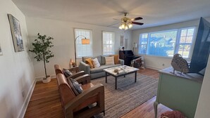 Un salón amplio con un conjunto de sofás, una mesa de centro y un televisor sobre un mueble.