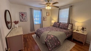 A bedroom with a bed, nightstands, a dresser, a ceiling fan, and a window with blinds. - Cozy Camellia Cottage – Minutes to Downtown & Augusta National (Augusta)