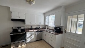 A kitchen with white cabinets, a stove, a dishwasher, and a window with blinds. - Cozy Camellia Cottage – Minutes to Downtown & Augusta National (Augusta)