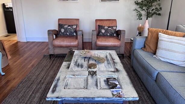 A living room with two leather armchairs, a coffee table with a rustic design, and a grey sofa with decorative pillows. - Cozy Camellia Cottage – Minutes to Downtown & Augusta National (Augusta)