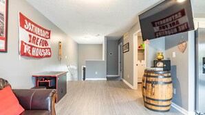 A hallway with a pool table, a wooden barrel, and a sign that reads "SATURDAY'S ARE FOR THE HOOSERS". - Memorial Field Lodge - 4 Bd Townhome by IU Sports (Bloomington)