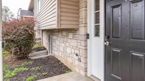 A house with a stone facade, a black front door with the number 4, and a small garden with plants and mulch. - Memorial Field Lodge - 4 Bd Townhome by IU Sports (Bloomington)