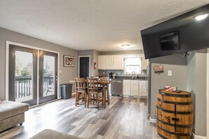 Un espacio habitable amplio con mesa y sillas de comedor, una cocina con armarios blancos y un balcón con vistas.