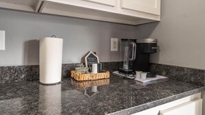 Een keuken met een granieten aanrecht, een koffiezetapparaat, een keukenpapierhouder en een welkomstbord.