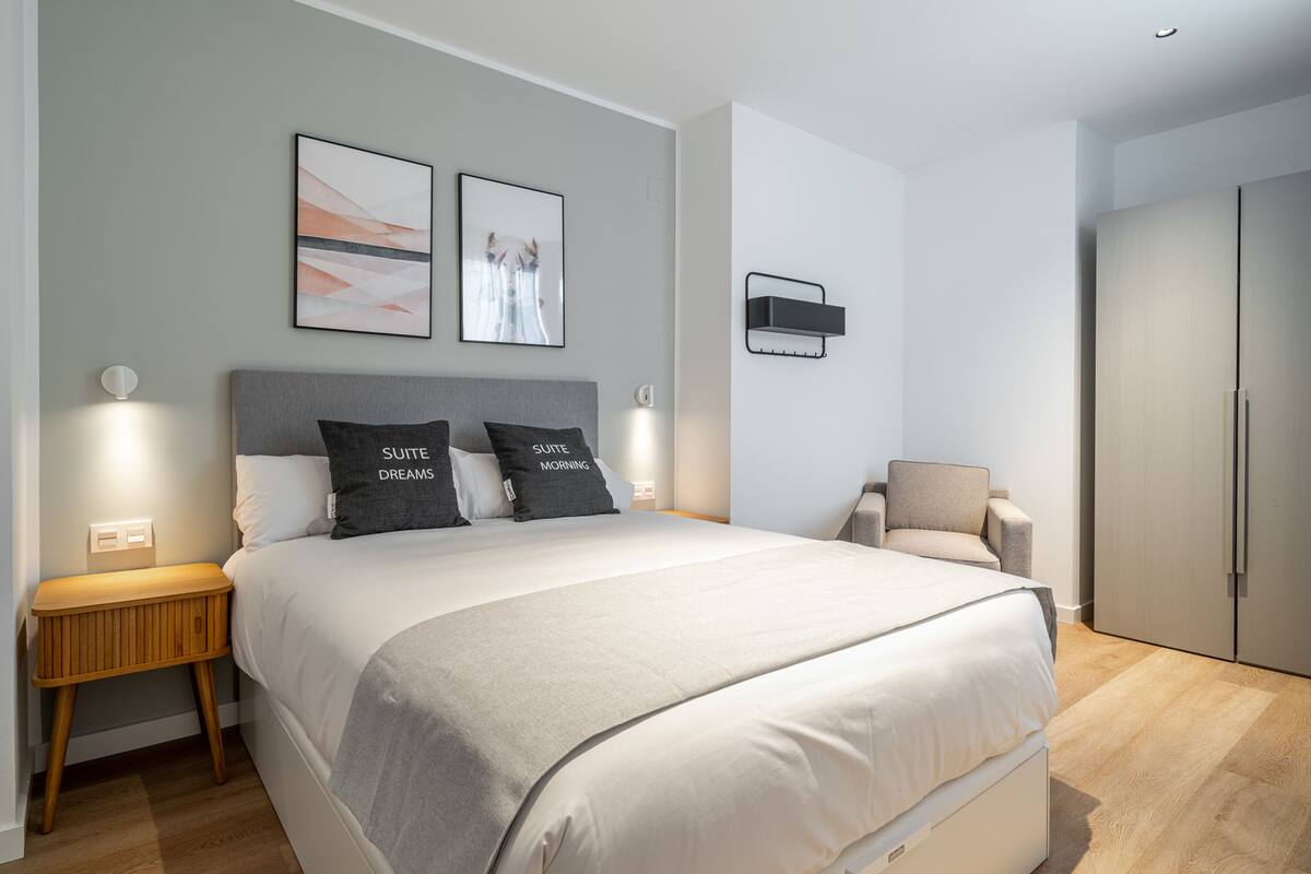 Une chambre à coucher moderne avec un grand lit, des tables de chevet, une chaise et une armoire.