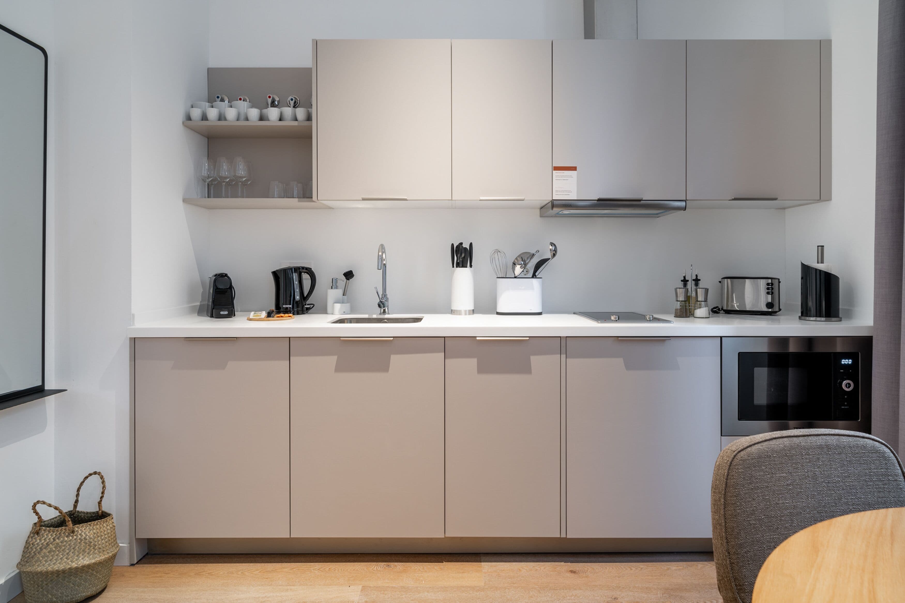 A modern kitchen with a white countertop, grey cabinets, and a built-in microwave.