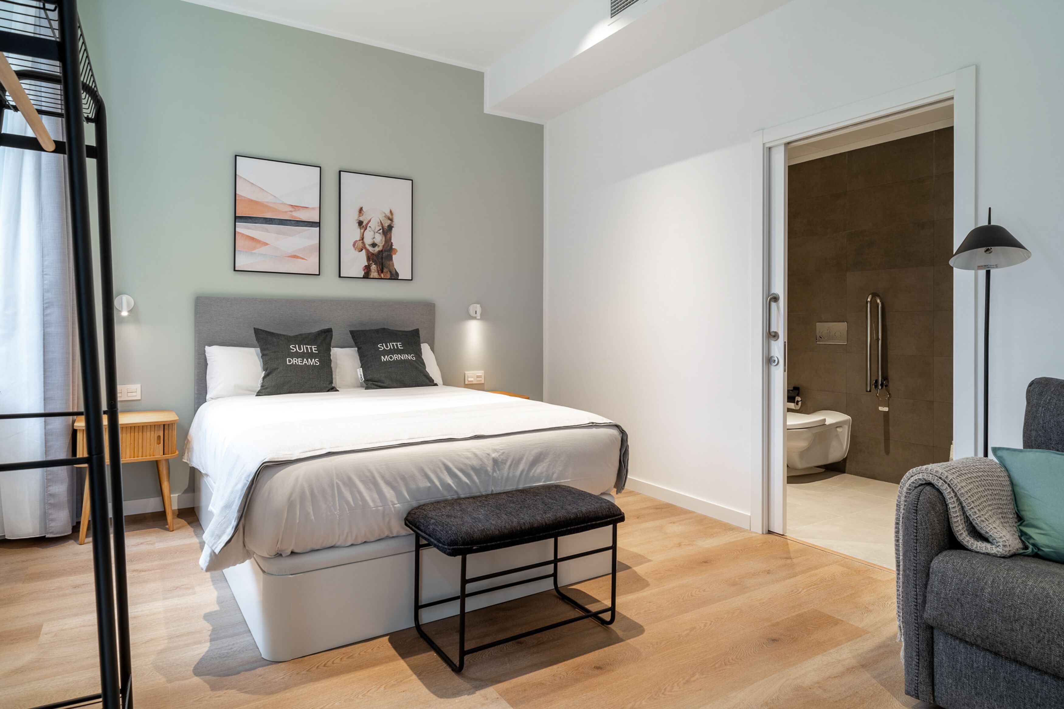 Un dormitorio moderno con cama, banco y una obra de arte en la pared.