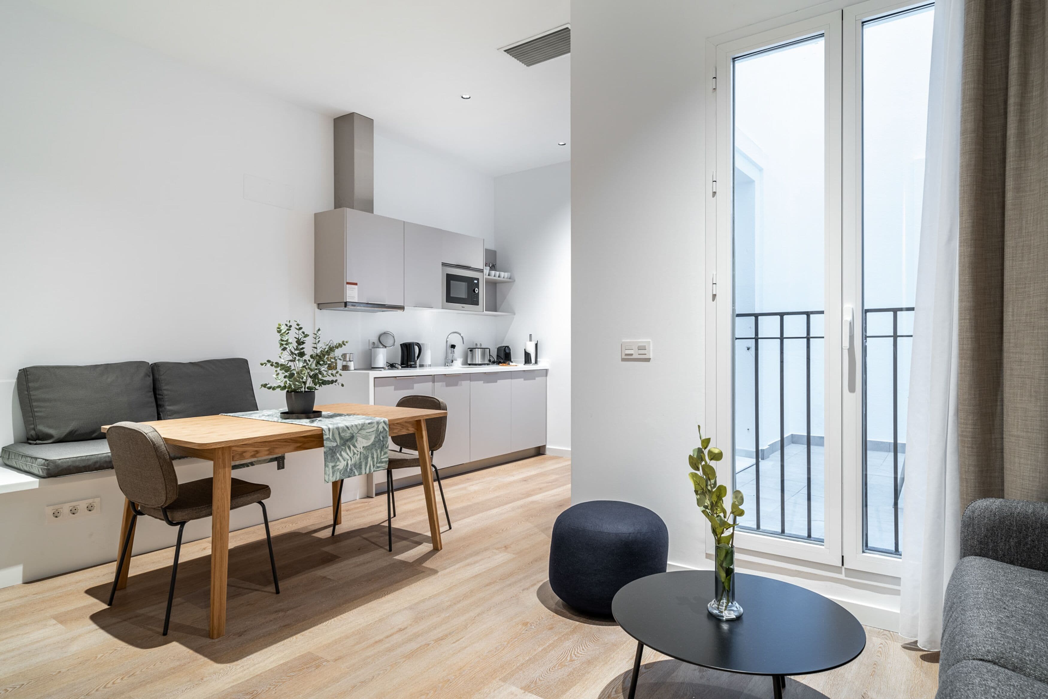 A modern apartment with a dining area, kitchen, and balcony.