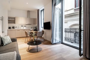 A modern apartment with a dining area, kitchen, and a balcony with wrought iron railings.