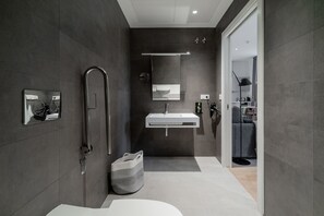 Un baño moderno con cabina de ducha, lavabo integrado y un espejo grande.