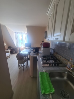A compact kitchen with a gas stove, a sink, and a dining area with a chair and table. - Un Tuffo nel Mare by PortofinoVacanze (Santa Margherita Ligure)