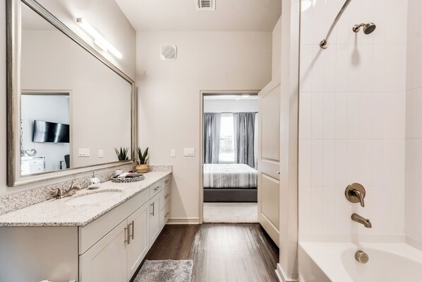 Un baño moderno con un espejo grande, una bañera y una ducha.