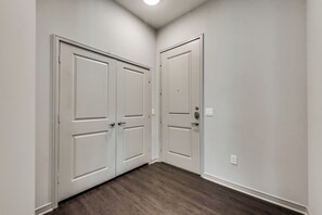 Un pasillo con dos puertas blancas, un interruptor de luz y un enchufe en la pared.