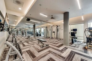 A gym with various exercise equipment, mirrored walls, and a patterned floor.