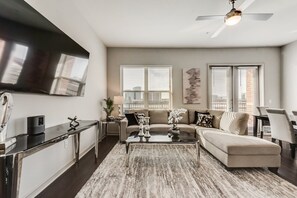 A modern living room with a sofa, coffee table, and a flat-screen TV mounted on the wall. - LC058-3 - Home|Yard|8mi to Fair Park|Sleeps 6 (Irving)