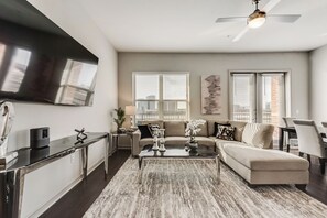 A modern living room with a flat-screen TV, a sofa, a coffee table, and a ceiling fan.