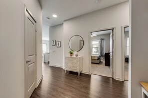 A hallway with a white door, a white console table with a mirror, and a plant.