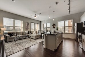 A modern kitchen with a central island, large windows, and a dining area with a sofa and coffee table. - LC058-3 - Home|Yard|8mi to Fair Park|Sleeps 6 (Irving)