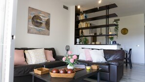Una sala de estar moderna con un sofá de cuero oscuro, una mesa de centro con objetos decorativos y una estantería llena de libros y adornos.