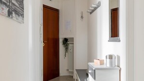 A hallway leading to a kitchen with a white countertop, a wooden door, and a wall-mounted mirror.