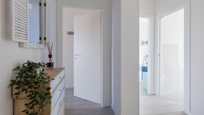 A hallway with a wooden dresser, a mirror, and a door leading to another room.