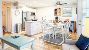 A modern kitchen with a central island, white cabinetry, and a dining area with a round table and chairs.