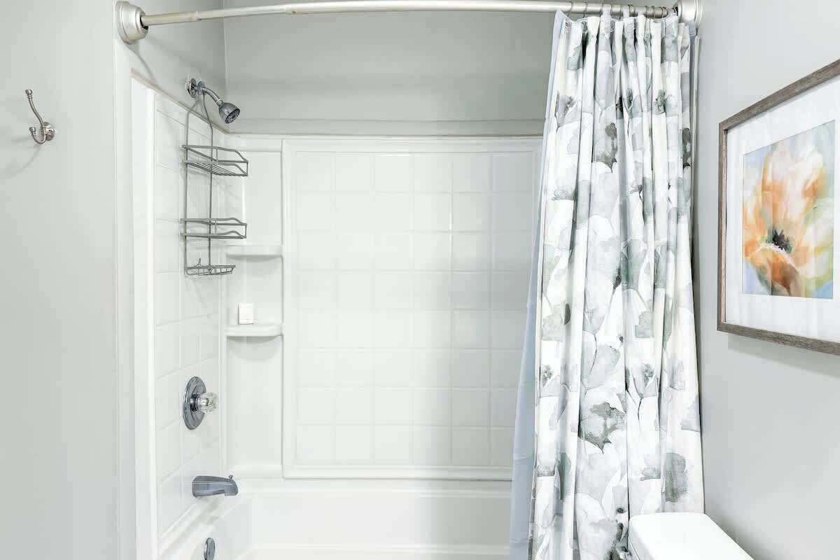 A bathroom with a shower, a toilet, a towel rack, and a framed picture on the wall.