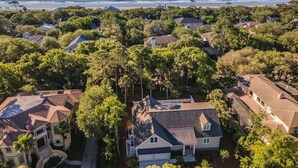 An aerial view of a coastal residential area with houses, trees, and a beach.