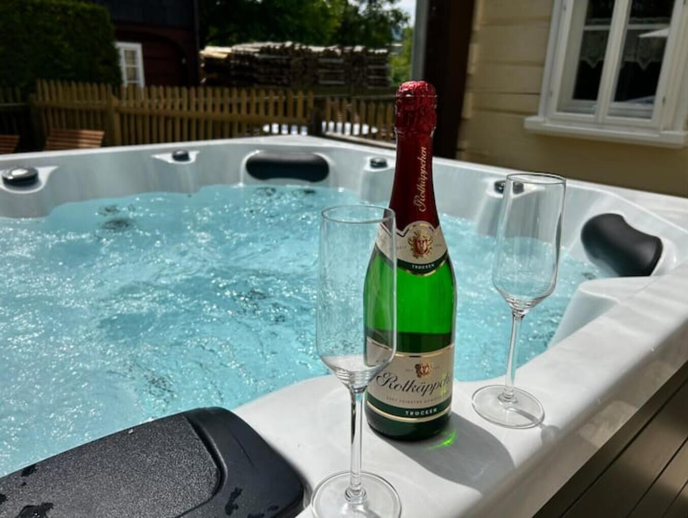 Ein Whirlpool mit einer Rottkappe Flasche und zwei Gläsern am Rand.