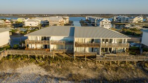A beachfront property with a large house featuring multiple balconies, a wooden deck, and a view of the ocean. - Oceanfront Queen's Grant Condo "Tide-the-Knot" with Breathtaking Ocean Views! (Topsail Beach)